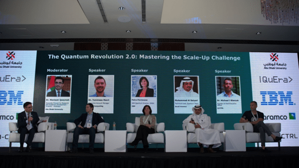 people sitting on a stage with a large screen description automatically generated